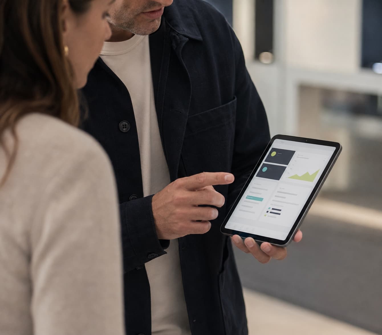 One professional showing a compact tablet dashboard to another person